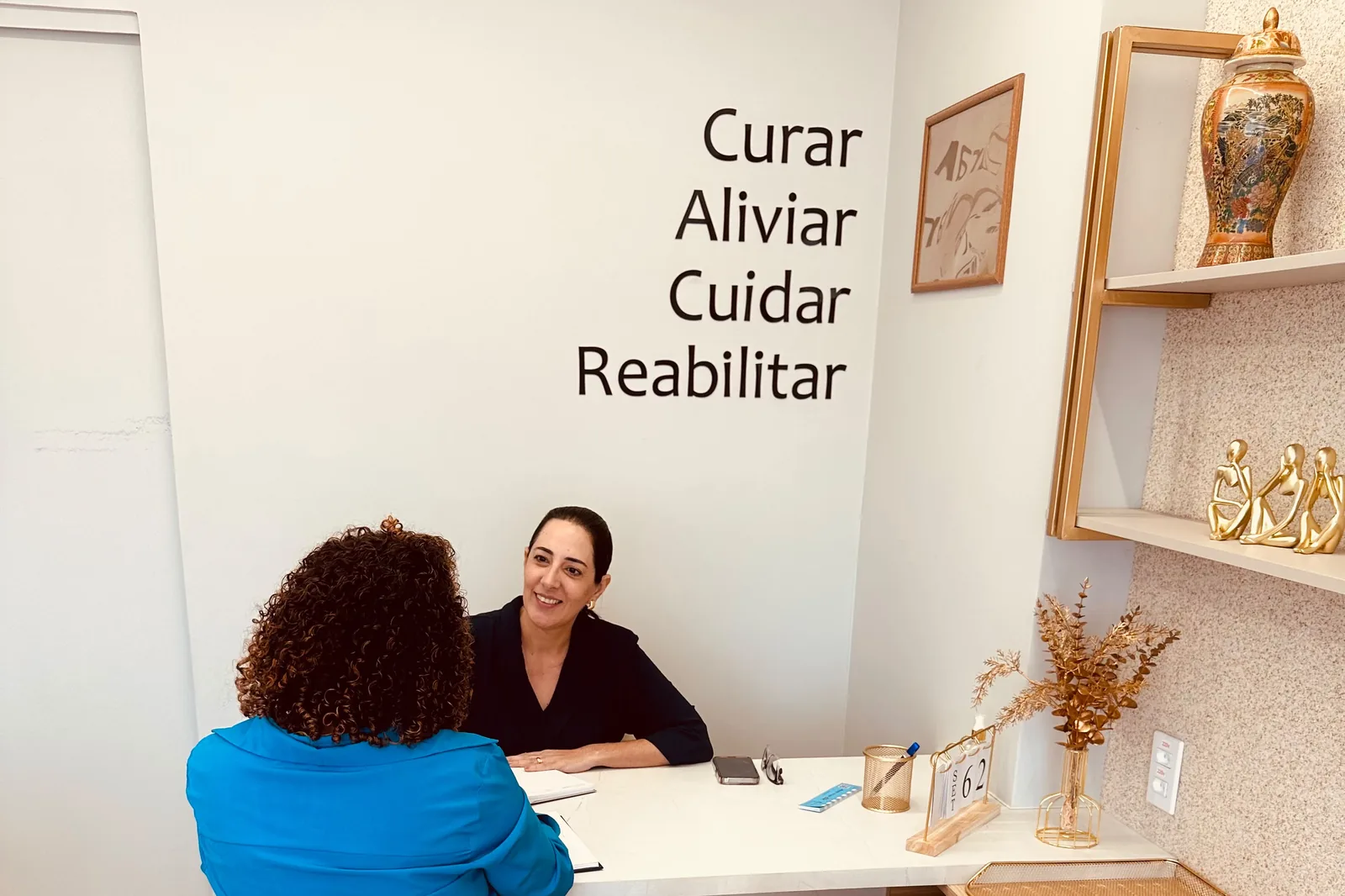 Sala de atendimento da Mazuchi Regenera com as palavras Curar, Aliviar, Cuidar e Reabilitar na parede